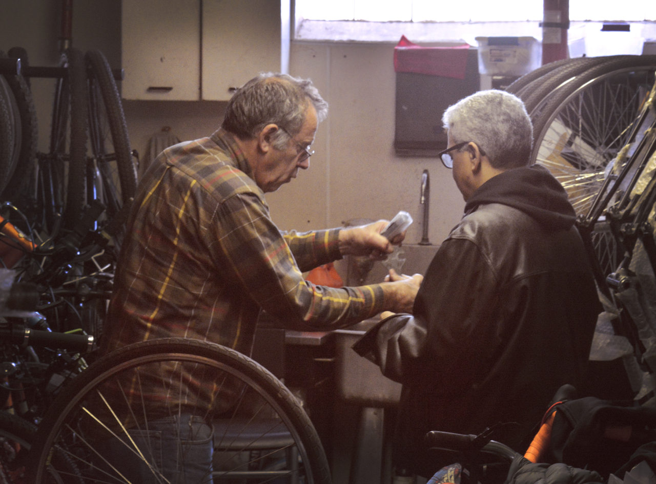 The man who is speaking is holding a bike tool,